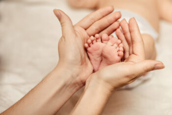 Mother holding tiny foot of newborn baby